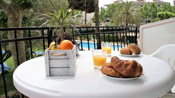 A round table with breakfast items including croissants, orange juice, and a fruit basket. - Apartaments Margarita Sabina Pinell (Castell-Platja d'Aro)