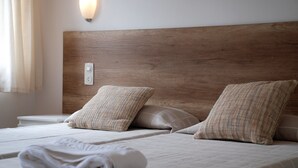A neatly made bed with a wooden headboard, two pillows, and a rolled white towel. - Apartaments Margarita Sabina Pinell (Castell-Platja d'Aro)
