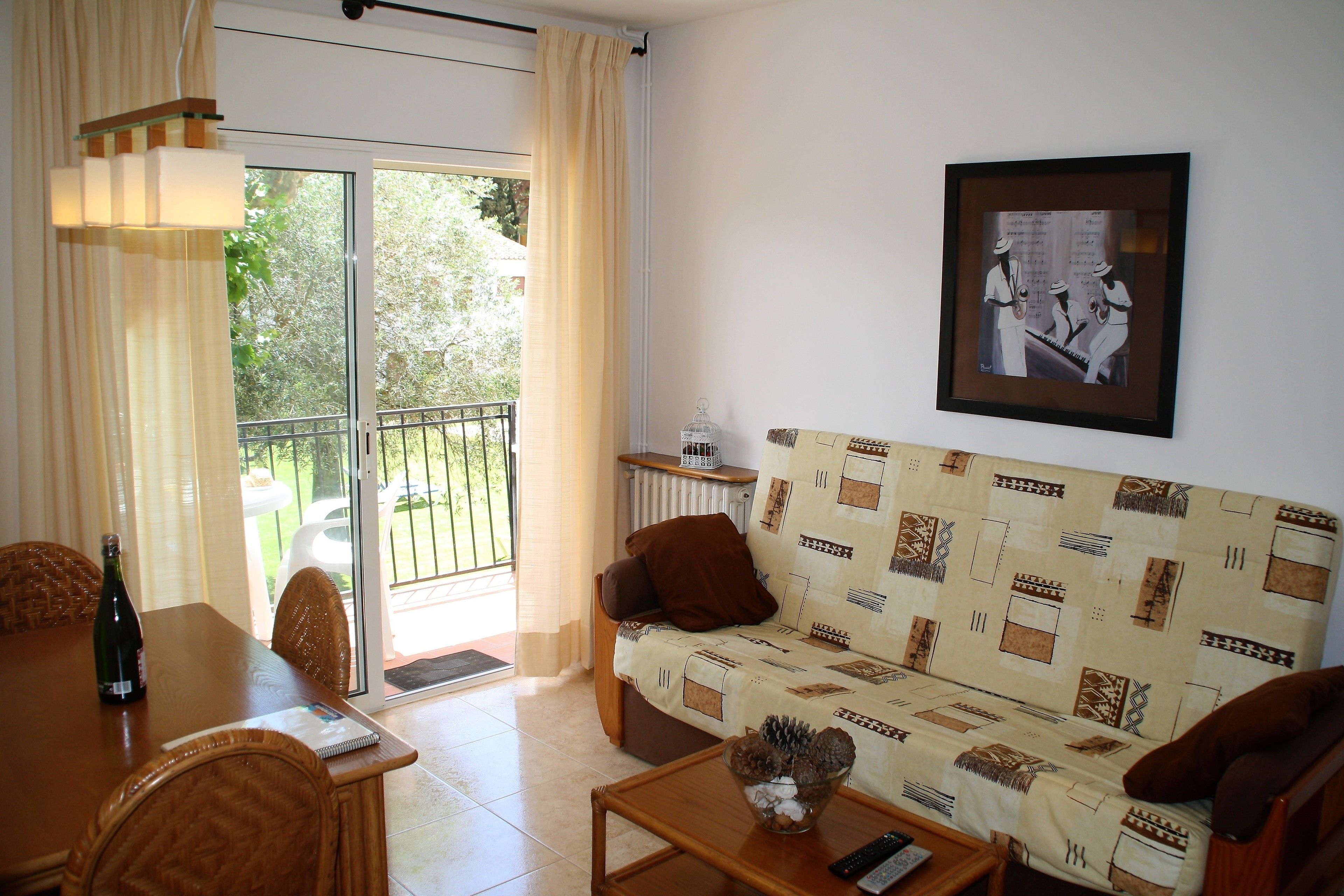 A living room with a sofa, a dining table with chairs, a coffee table, and a framed picture on the wall.