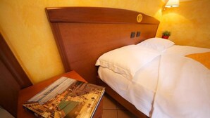 A hotel room with a wooden headboard, a bed with white bedding, and a nightstand with a magazine. - Villa Terri (Verona)