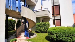 A modern building with a curved staircase leading to a balcony, surrounded by well-maintained lawns and potted plants. - Villa Terri (Verona)