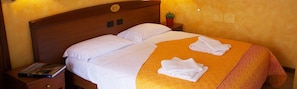 A hotel room with a double bed, two pillows, a bedside table with a book, a small plant, and a sign indicating the room number. - Villa Terri (Verona)