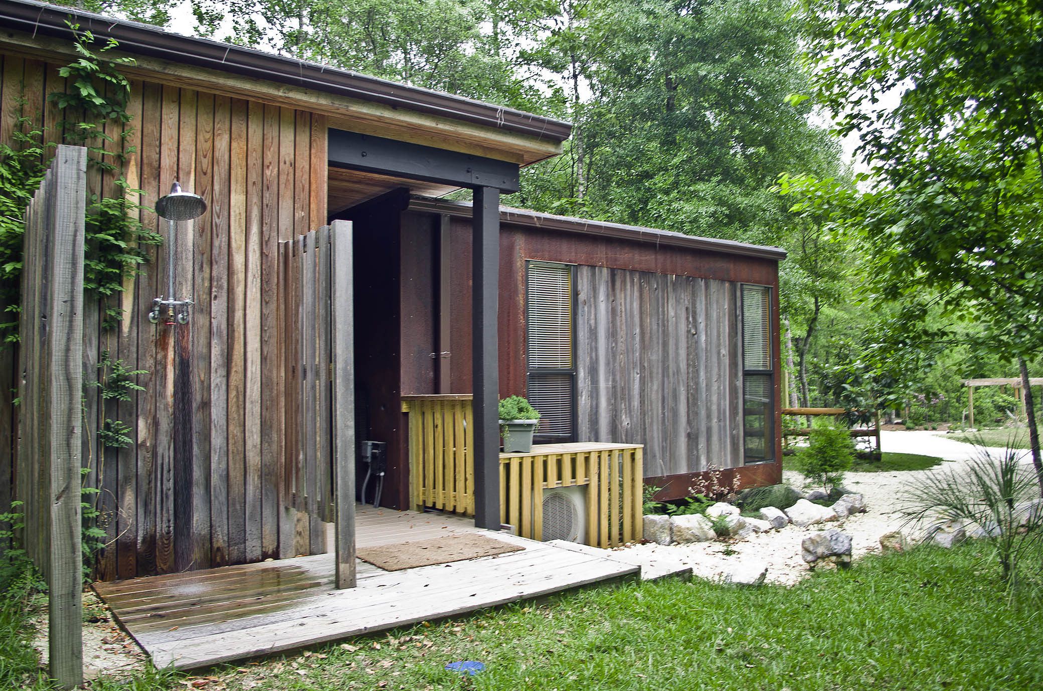 A rustic wooden building with a wooden deck and a small garden area.