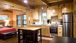 Una habitación acogedora tipo cabaña con una cama, una mesa de comedor y una kitchenette.