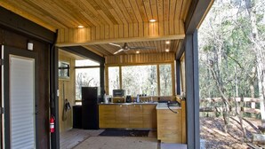 Una cocina moderna con armarios de madera, horno empotrado y un amplio ventanal con vistas a zona boscosa.