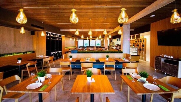 A restaurant with wooden tables and chairs, hanging light fixtures, and a bar area. - Residence Trafick (Praha)