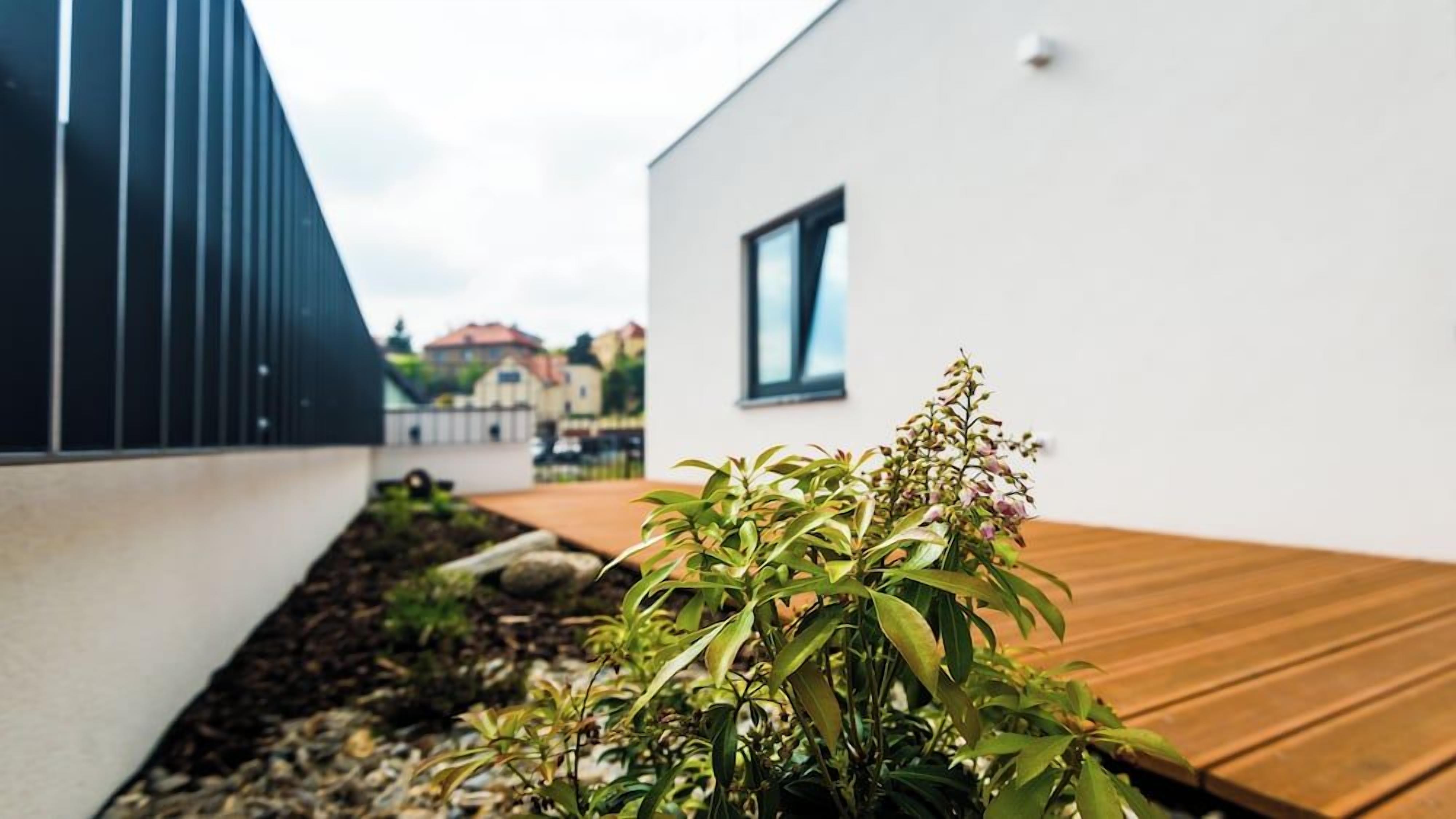 Un edificio moderno con terraza de madera y jardín con plantas.