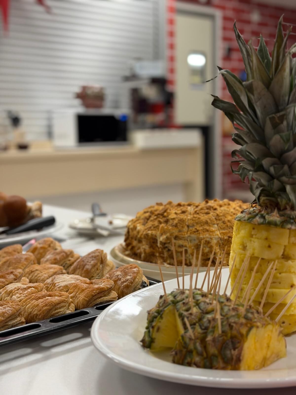 A buffet table with various food items including pastries and a pineapple.