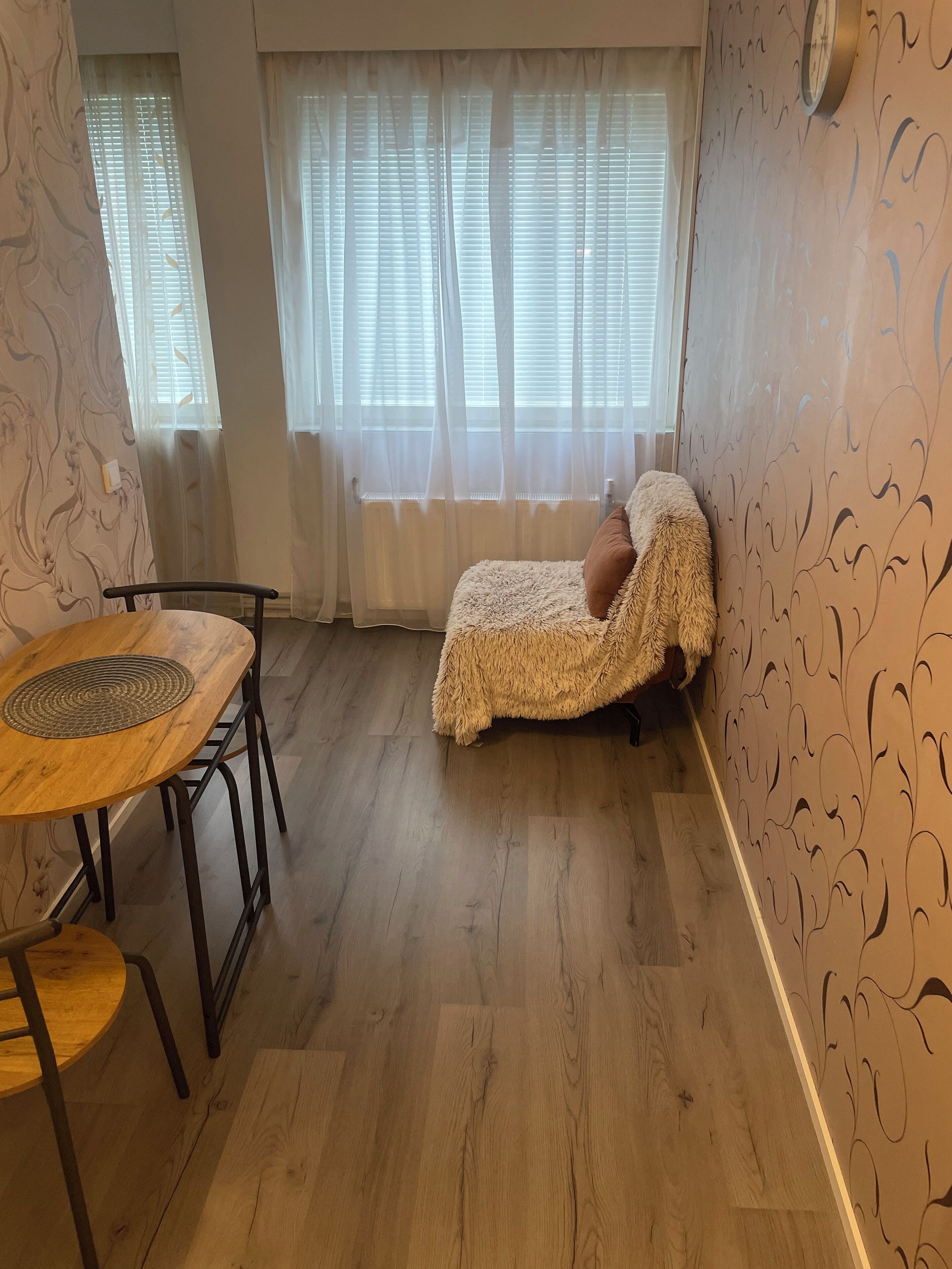 Una habitació acollidora amb un llit individual, una taula de fusta i una cadira.