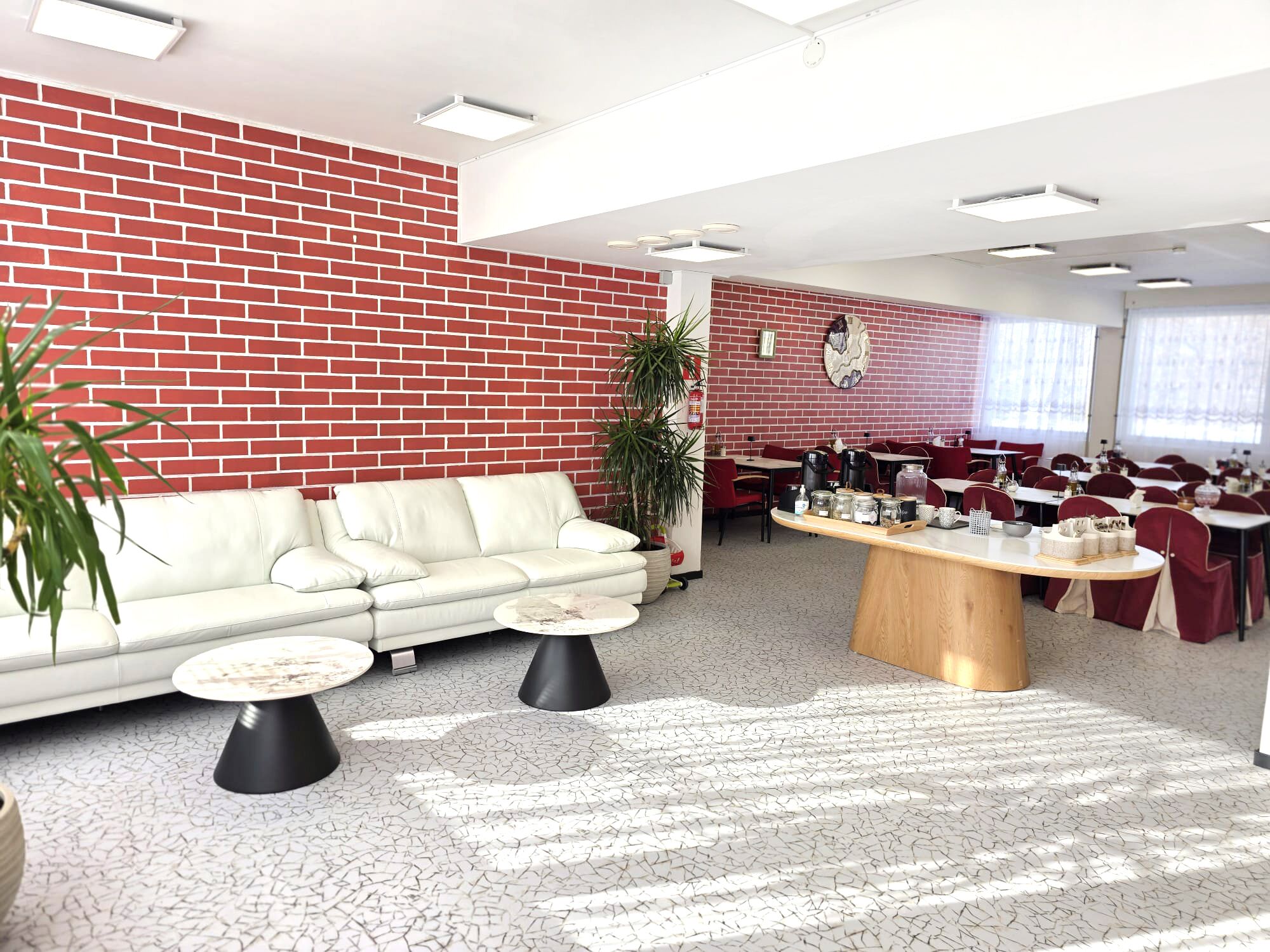 A modern interior with a brick wall, a white sofa, black coffee tables, and a wooden central table with items on it.
