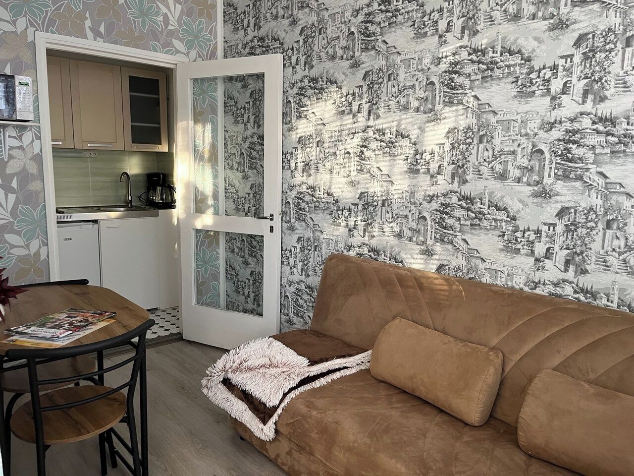 A compact living space with a kitchenette, a sofa, and a dining table.