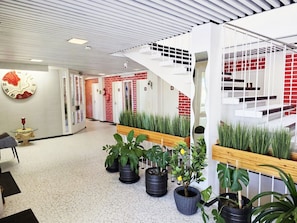 A modern interior with a white ceiling, a spiral staircase, and potted plants. - Hotel Ilomantsi North Star (Ilomantsi)