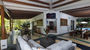 A covered outdoor area with a sofa, a coffee table, and a dining table. - Casa Cedro - Portasol Vacation Rentals (Savegre)