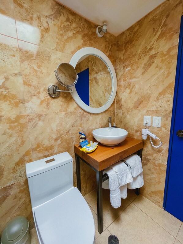 Un baño con inodoro, lavamanos, espejo y toallero.