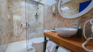 Un bagno moderno con doccia in vetro, lavandino bianco, specchio rotondo e porta asciugamani.