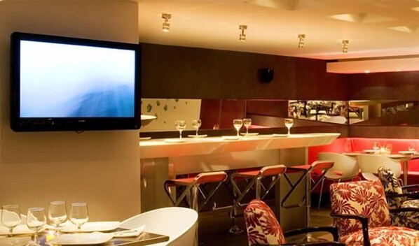 Un restaurante con zona de bar, varias mesas y sillas.