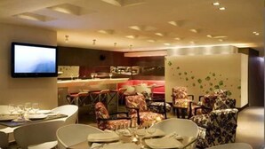 A modern dining area with a bar, multiple seating arrangements, and a flat-screen TV mounted on the wall. - San Simon Hotel Boutique (Pereira)