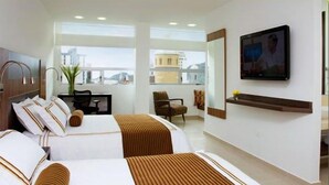 A hotel room with two beds, a desk, a chair, a TV, and a large window. - San Simon Hotel Boutique (Pereira)