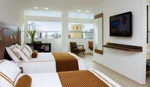 Een hotelkamer met twee bedden, een bureau, een stoel, een televisie en een groot raam.
