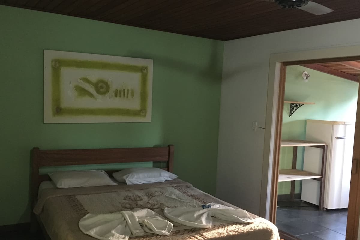 Une chambre à coucher avec un lit, un ventilateur de plafond et un mur vert.
