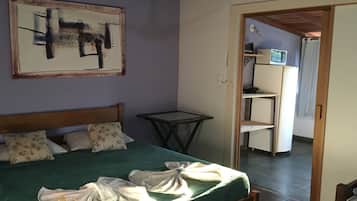 Quarto com cama, mesa e um quadro na parede.