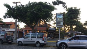 A cobblestone street with parked cars and a McDonald's restaurant. - Anexo Aldeia Buzios – Cama & Café (Búzios)