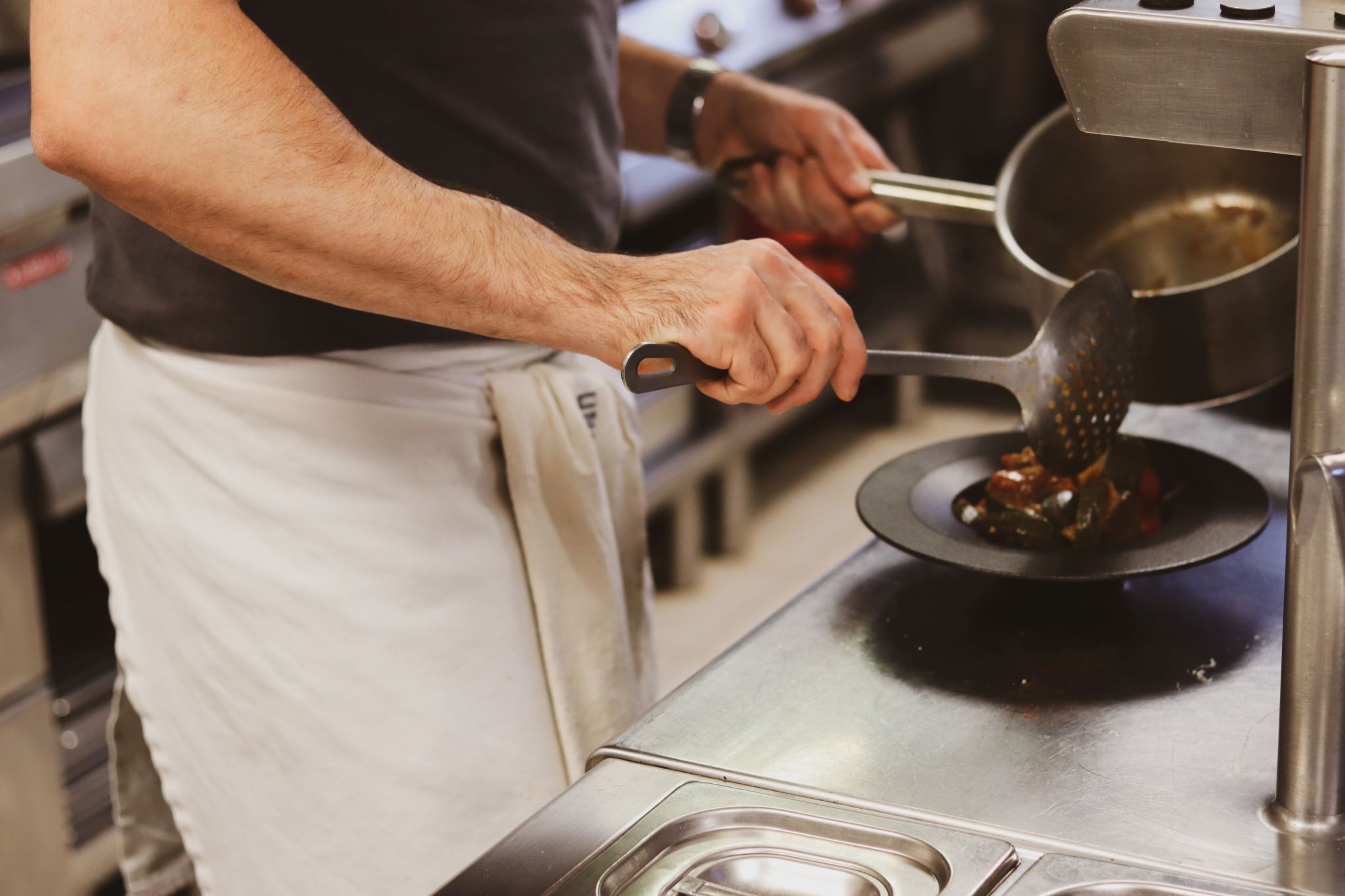 A person using a grater on a stove in a kitchen.