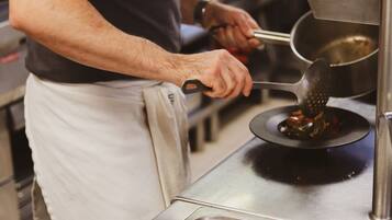 A person using a grater on a stove in a kitchen.