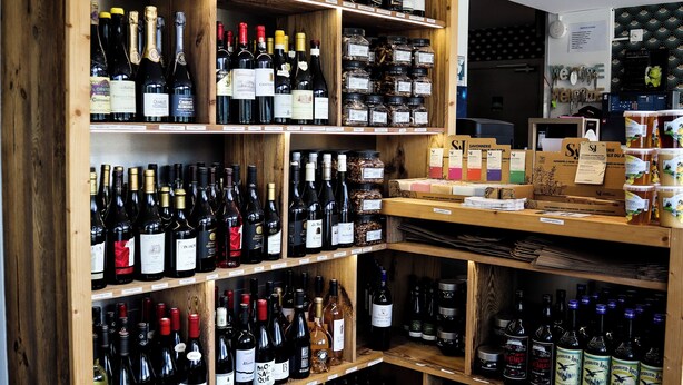 A wine shop with wooden shelves stocked with various bottles of wine. - Auberge du Château de Joux (La Cluse-and-Mijoux)