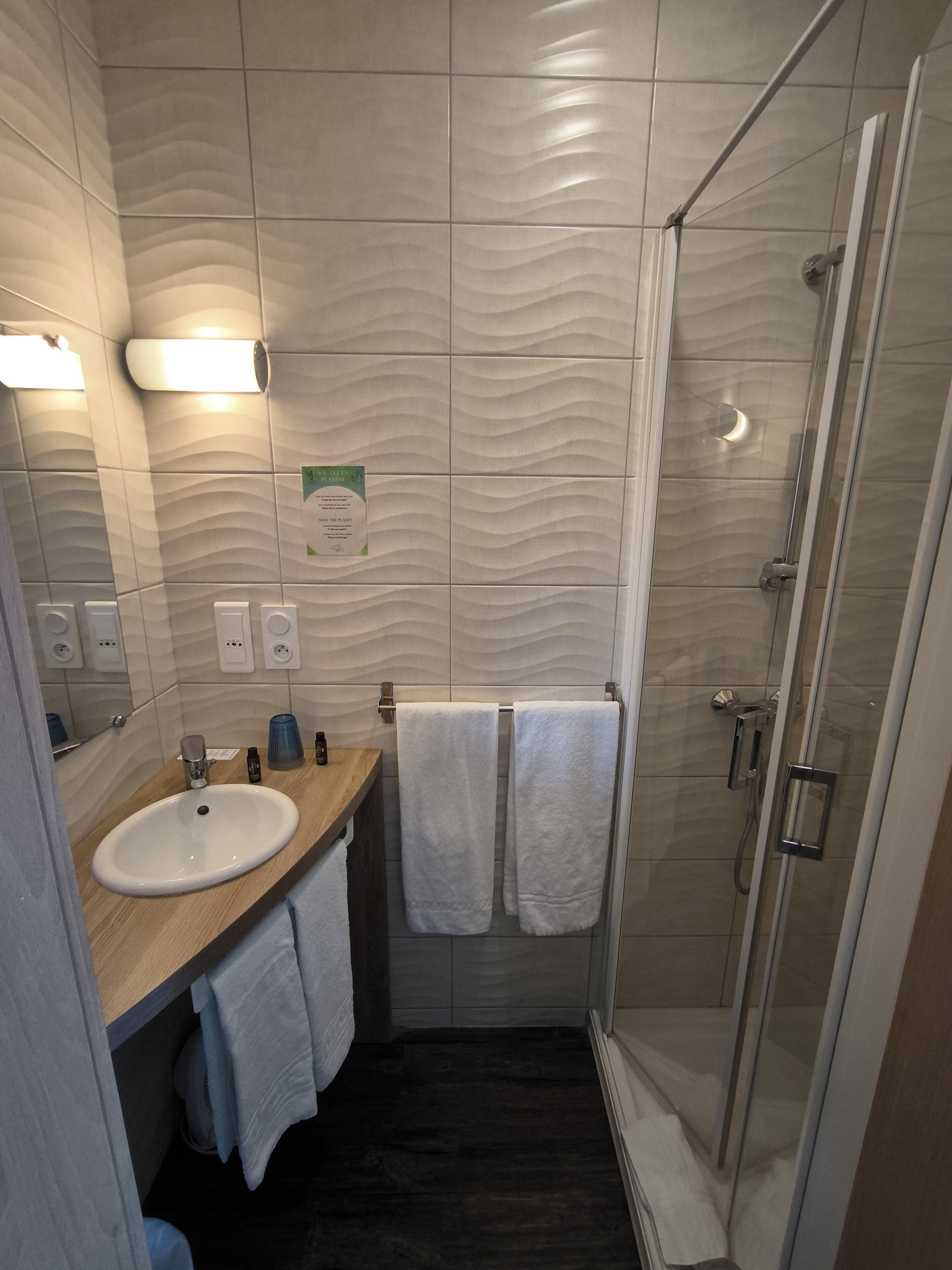 Ein modernes Badezimmer mit Waschbecken, Spiegel, Handtuchhalter und Duschkabine.