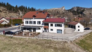 A hotel with a red roof, outdoor seating, and a view of a hill with a castle. - Auberge du Château de Joux (La Cluse-and-Mijoux)