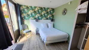 A bedroom with a bed, a chair, a nightstand, a wall-mounted light, and a view of the outside. - Auberge du Château de Joux (La Cluse-and-Mijoux)