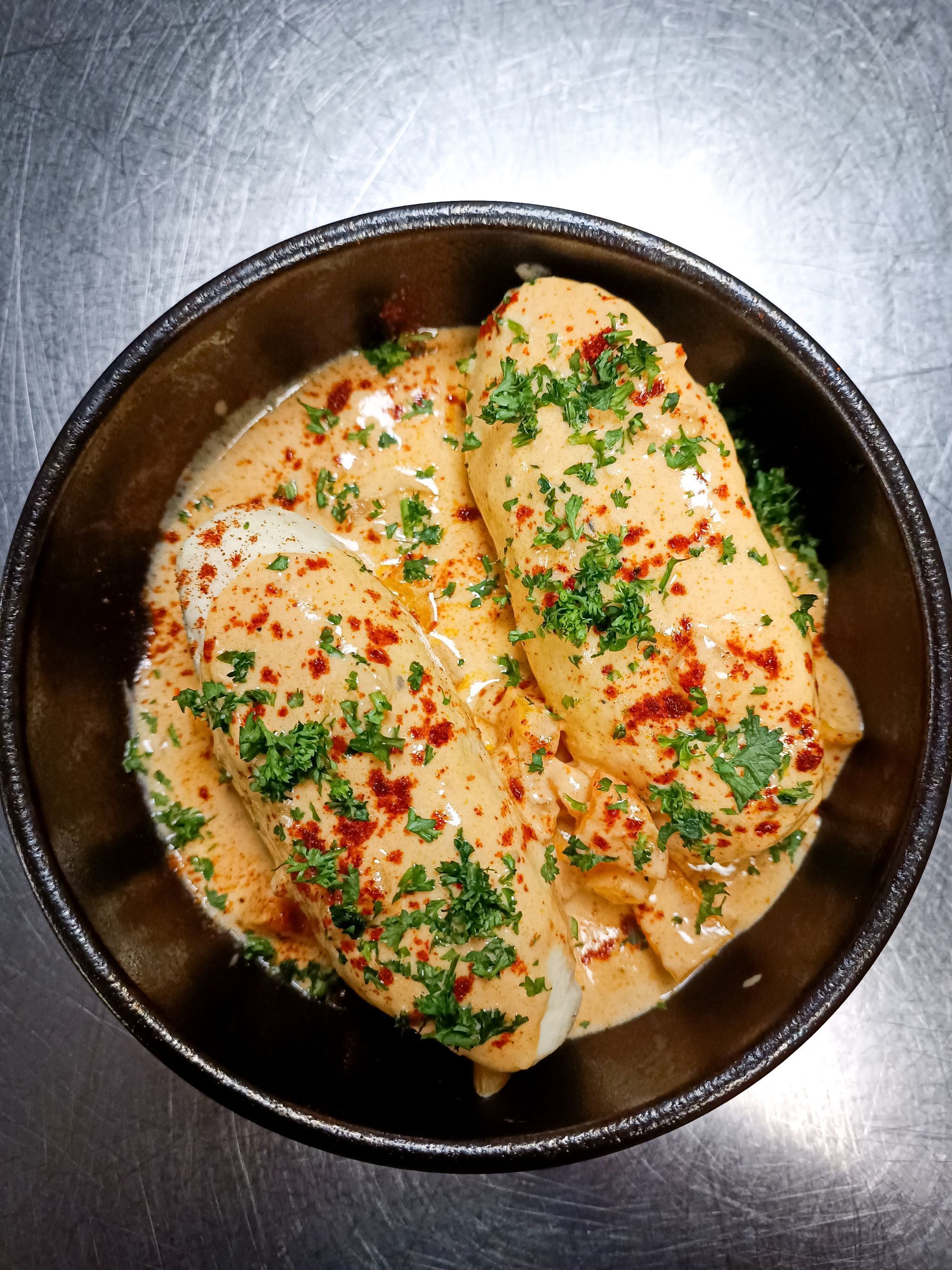 Uma tigela de comida com molho cremoso, guarnecida com ervas e especiarias.