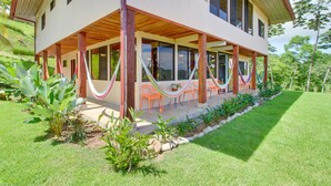 A two-story house with a covered patio area, outdoor seating, and a hammock. - Valley of Dreams Eco Lodge Room (Barú)