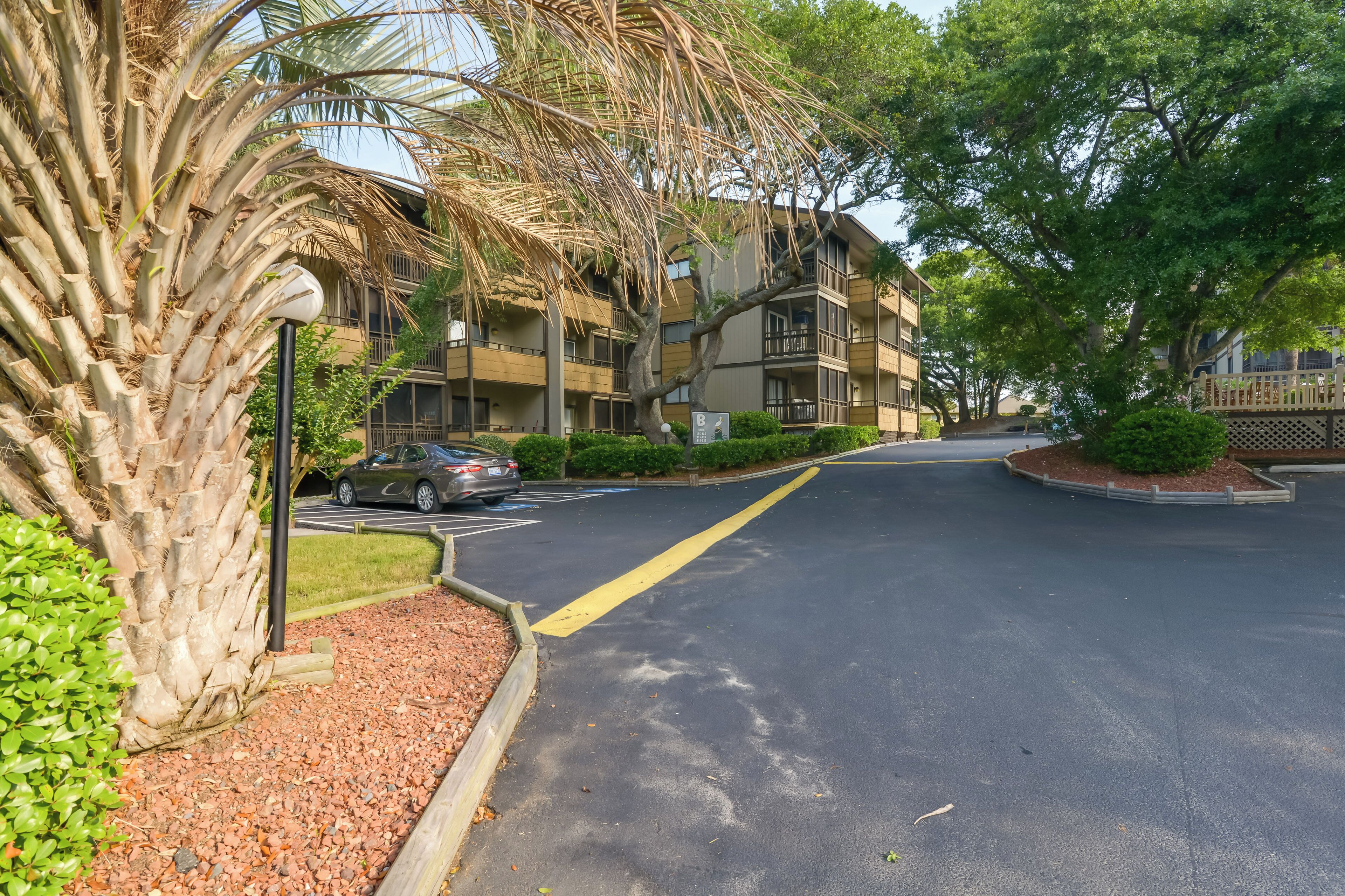 A residential street with a row of multi-story buildings, a palm tree, and a parking area.