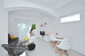 A modern living room with a sofa, a dining table with chairs, a TV, and a window. - Beautiful Studio near beach in Zadar Diklo (Zadar)