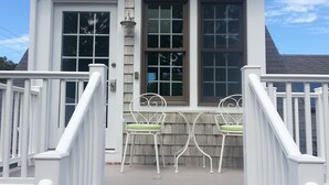 A white house with a porch, two chairs, and a small table. - 5BR-Beautiful Chatham-Year Round-Sleeps up to ten (10) & 1 Mile to Town! (Chatham)