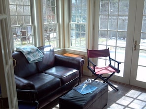 Relax in this inviting living room with a sofa, ottoman, and a view of the outdoors.