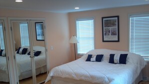 A bedroom with a large bed, a mirror, and two windows with blinds. - 5BR-Beautiful Chatham-Year Round-Sleeps up to ten (10) & 1 Mile to Town! (Chatham)