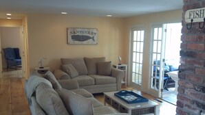 A living room with a grey sofa, a coffee table, and a wall sign that reads "NANTUCKET". - 5BR-Beautiful Chatham-Year Round-Sleeps up to ten (10) & 1 Mile to Town! (Chatham)