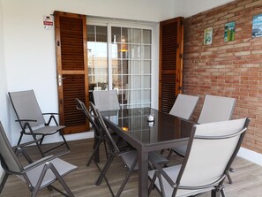 A glass-top table with four chairs, a wooden door, and a brick wall with posters. - ROSERS - House with private pool, barbecue 20 minutes Barcelona (Cabrils)