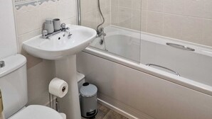 A bathroom with a toilet, sink, and bathtub. - Mayflower Coach House (Hereford)