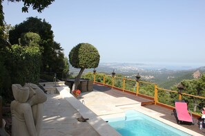 A pool area with a view of the landscape, a wooden deck, and a statue.