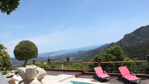 A pool area with a view of the mountains, two pink lounge chairs, and a stone sculpture. - Stunning Views Over The Bay Of Cannes (Fréjus)