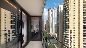 Un apartamento moderno con balcón, ventanas amplias y vistas a edificios altos circundantes.