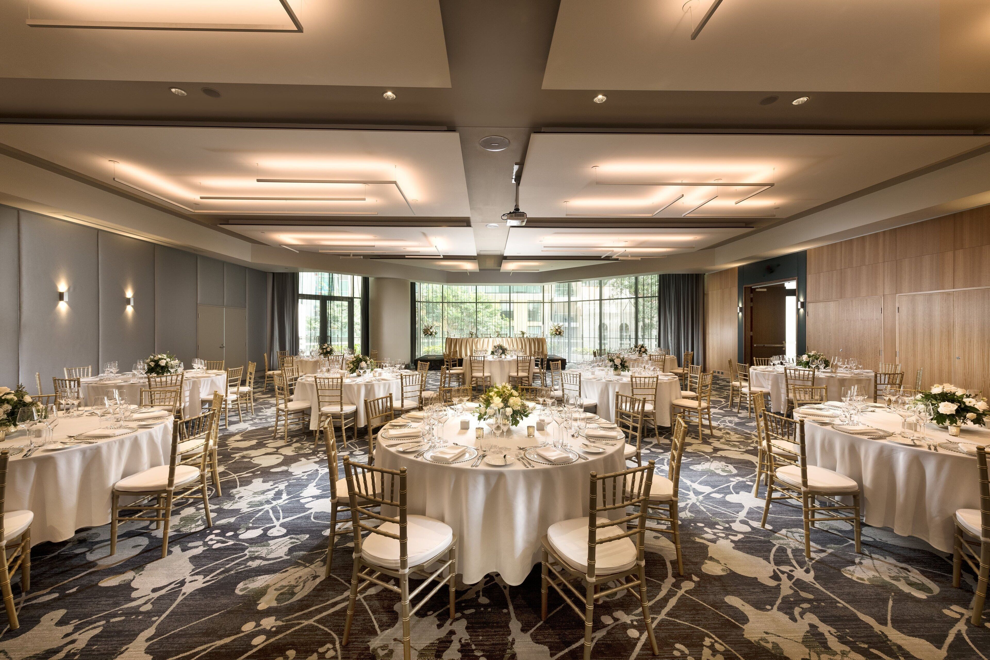 A large banquet hall with round tables set for dining, equipped with chairs and table settings.