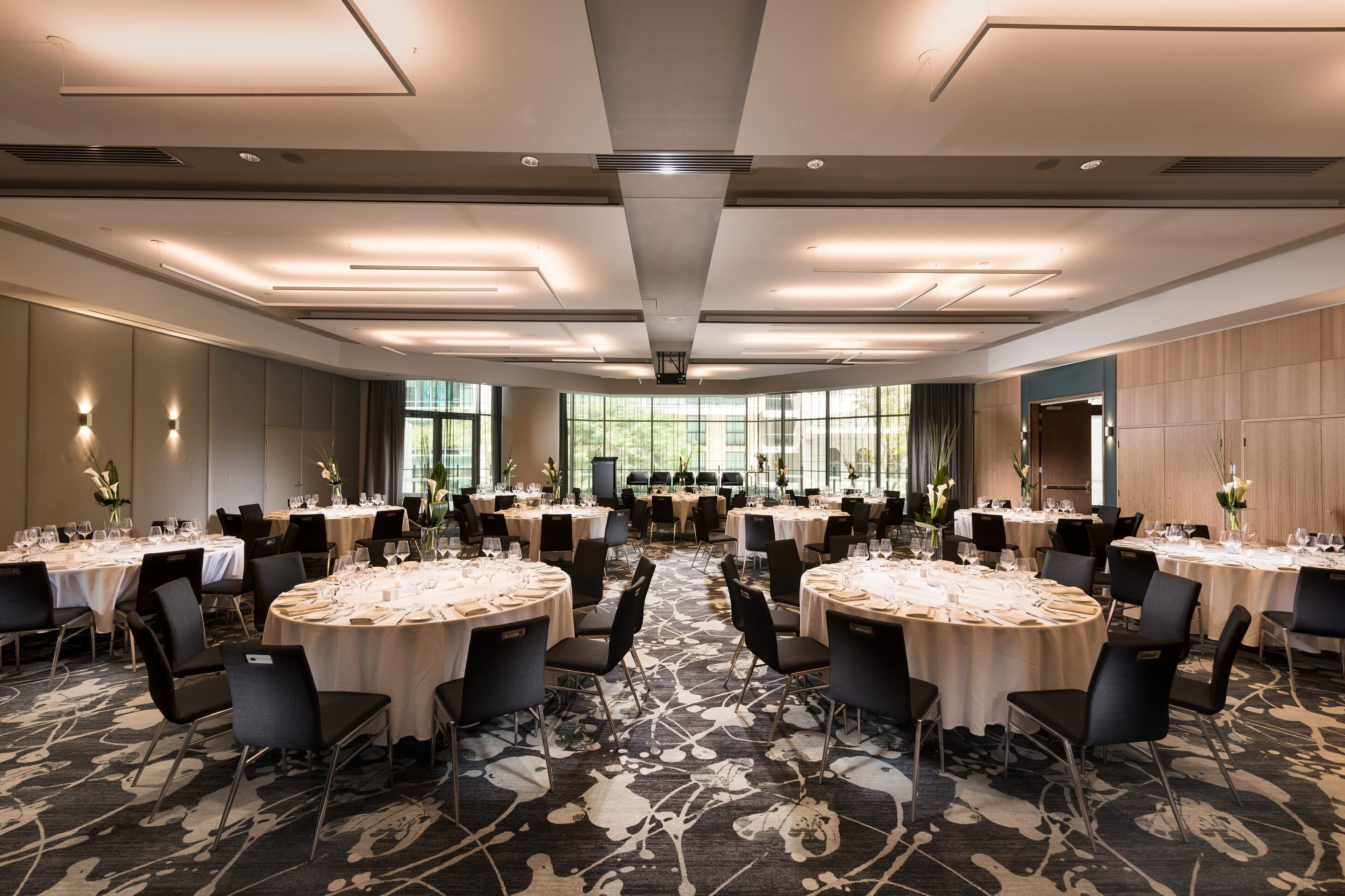 A large conference room with round tables, black chairs, and a carpeted floor.