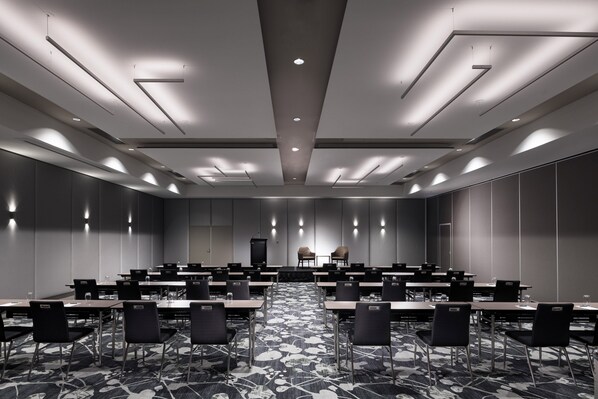 Un salón de conferencias con una larga mesa, sillas y un atril.