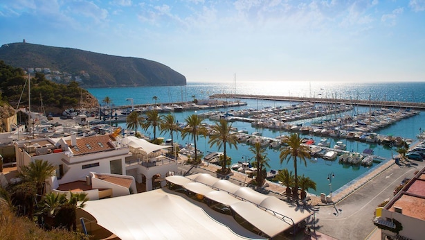 A marina with boats docked, a coastal road, and buildings with a hilly backdrop. - VILLA private pool, WiFi free, Air conditioning, Pet-friendly, 650m from town (Moraira)
