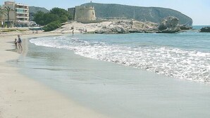 A beach with a rocky outcrop and a building in the background. - VILLA private pool, WiFi free, Air conditioning, Pet-friendly, 650m from town (Moraira)